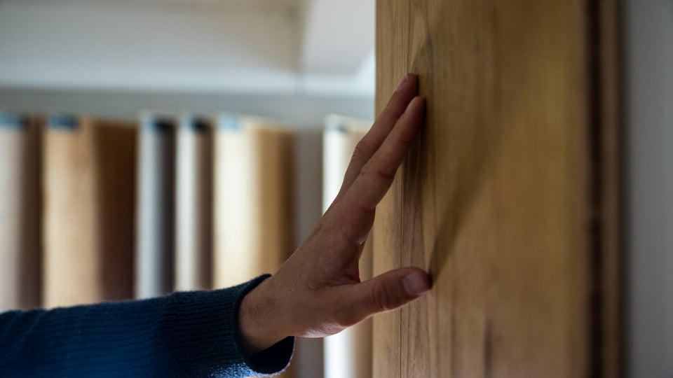 Hand mot trägolvsprov – materialkänsla och trästruktur