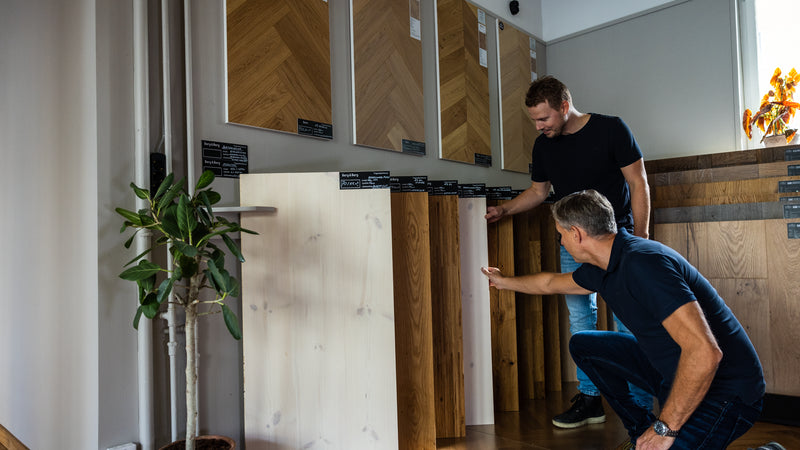 Två personer jämför golvprover i showroom – prisguide för golvläggning 2026