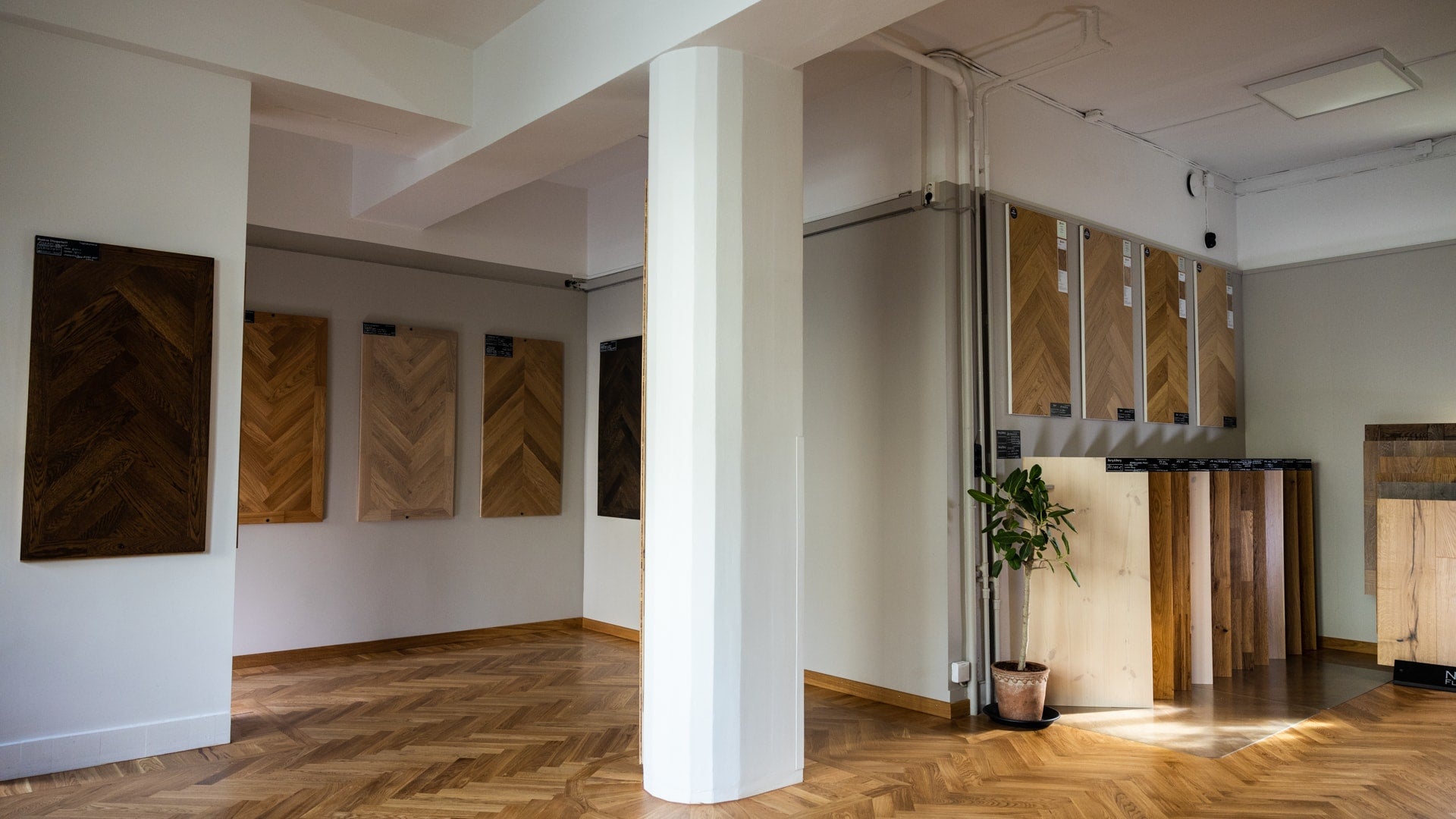 Bred interiörvy med kolonner, väggprover och stående paneler i showroom