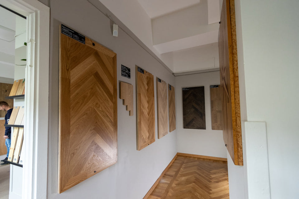 Tomt rumshörn med flera upphängda träprover och parkettgolv.